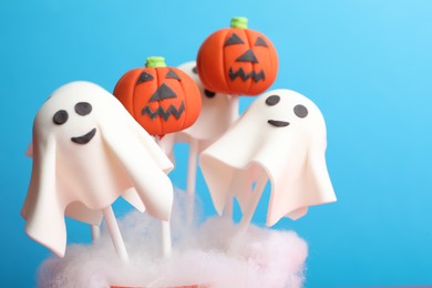 Photo of Delicious Halloween themed cake pops on light blue background, closeup