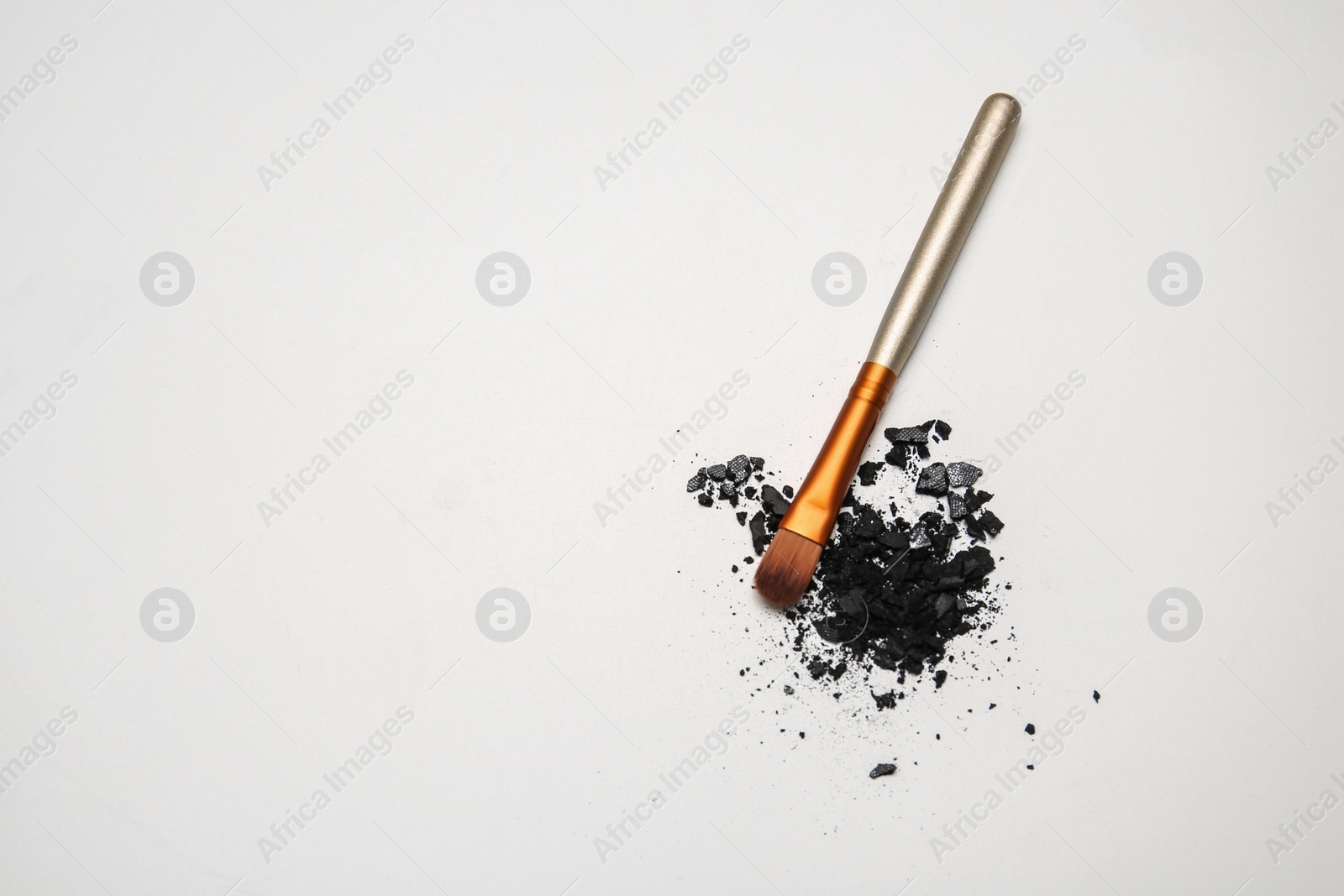 Photo of Makeup brush and crushed cosmetic product on white background, top view