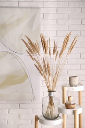 Photo of Fluffy reed plumes and painting in stylish room interior