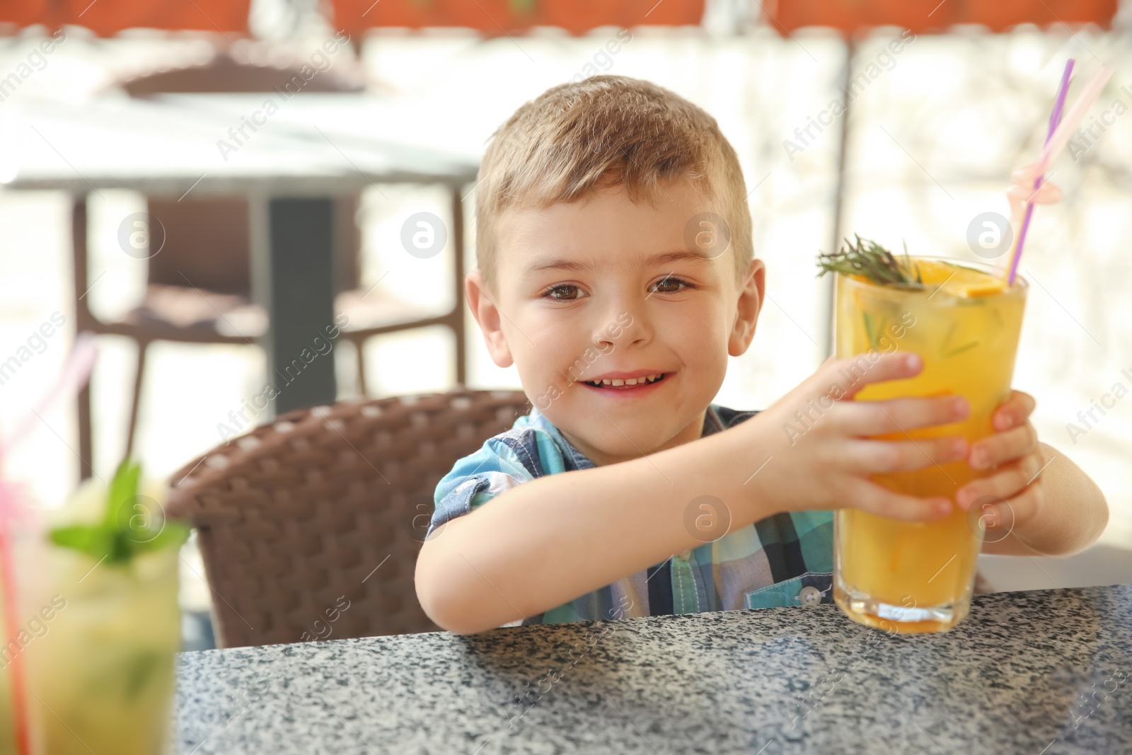 Photo of Cute boy with glass of natural lemonade at table in cafe