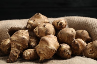 Photo of Jerusalem artichokes on bag against dark background, closeup