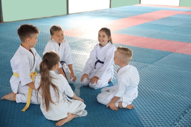 Photo of Group of children in kimono sitting on tatami after karate practice