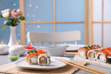 Different tasty sushi rolls and chopsticks on table, space for text