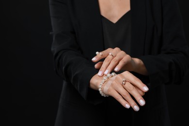 Photo of Young woman with elegant pearl jewelry on black background, closeup