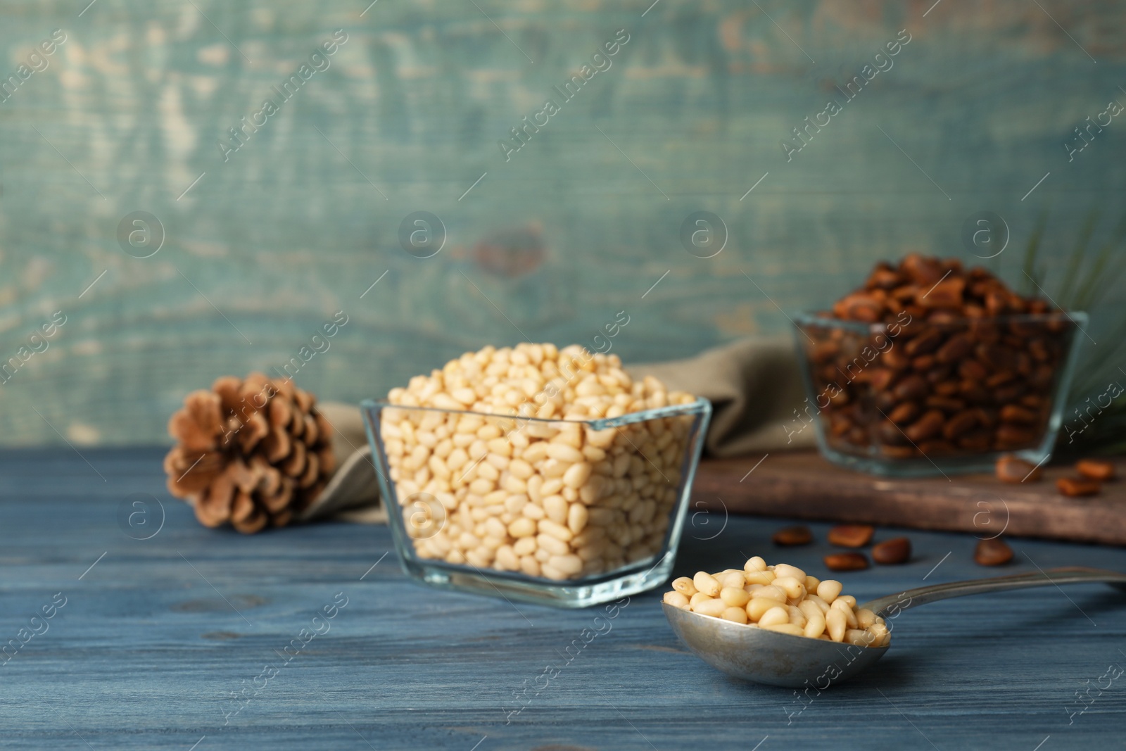 Photo of Spoon and bowl with pine nuts on wooden table