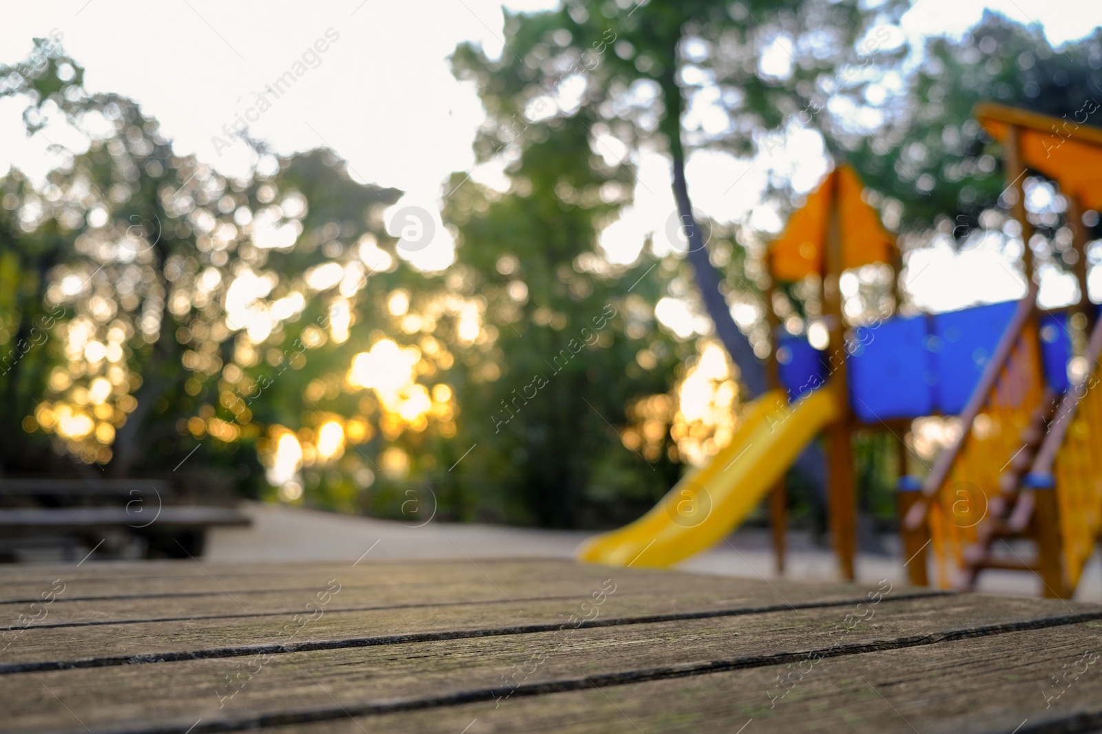 Photo of Wooden bench, beautiful slide and trees in park on sunny day