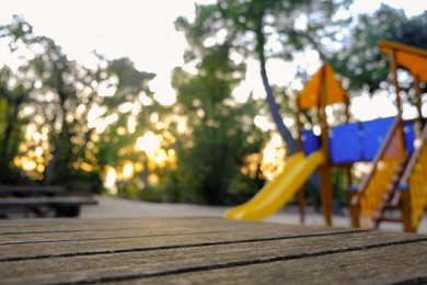 Wooden bench, beautiful slide and trees in park on sunny day