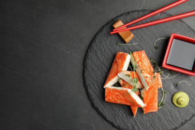 Fresh crab sticks with soy sauce served on black table, top view. Space for text