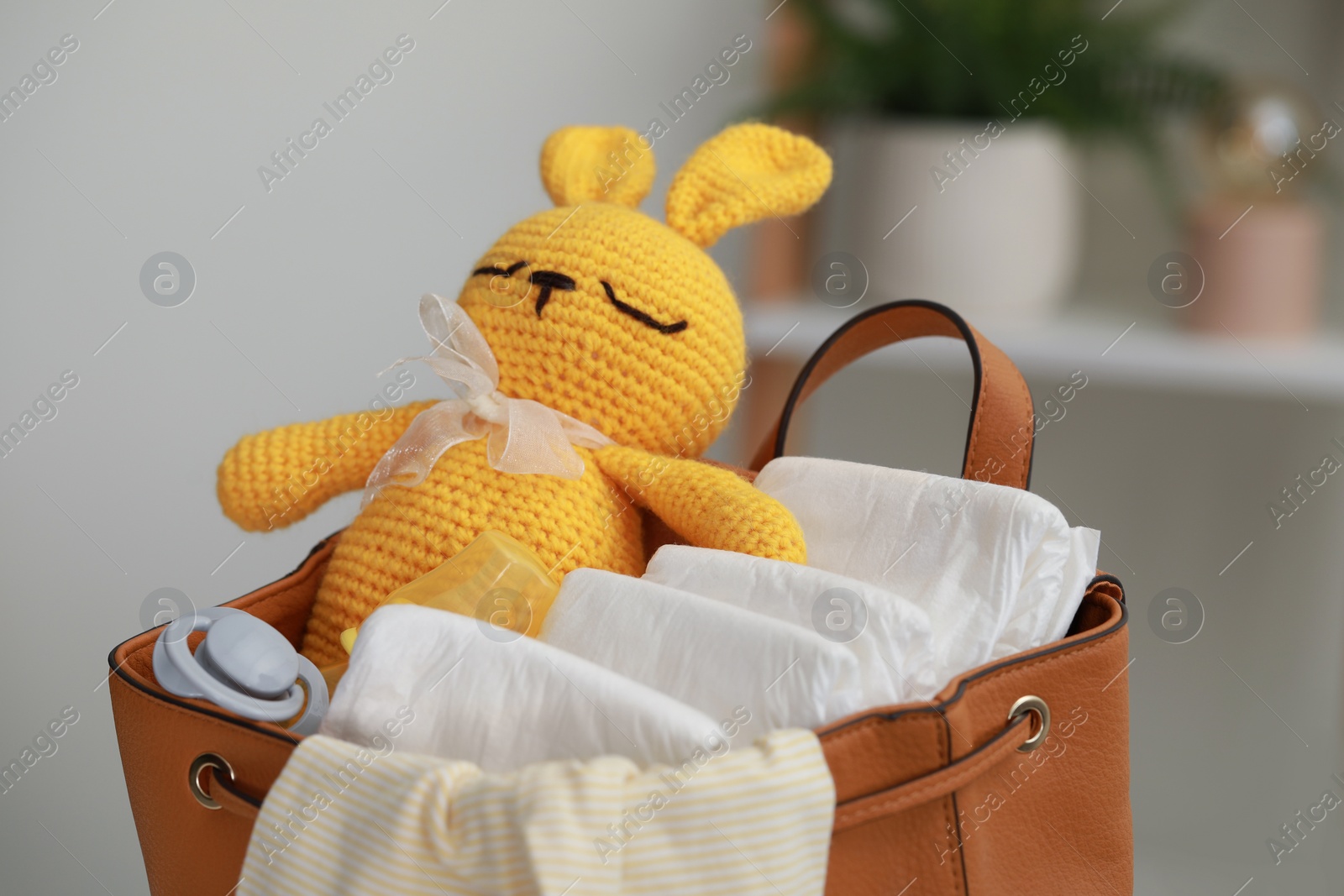 Photo of Mother's bag with baby's stuff indoors, closeup