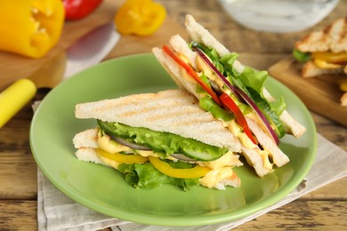 Photo of Green plate with tasty sandwiches on wooden table