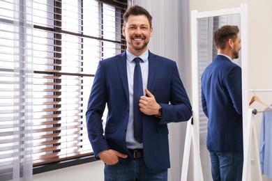 Photo of Confident man in office suit with necktie near mirror