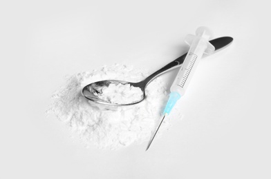 Photo of Spoon with cocaine and empty syringe on white background