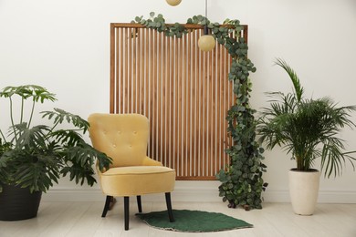 Photo of Stylish photo zone with wooden screen, floral decor and comfortable armchair indoors