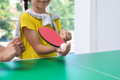 Photo of Little girl playing ping pong indoors, closeup