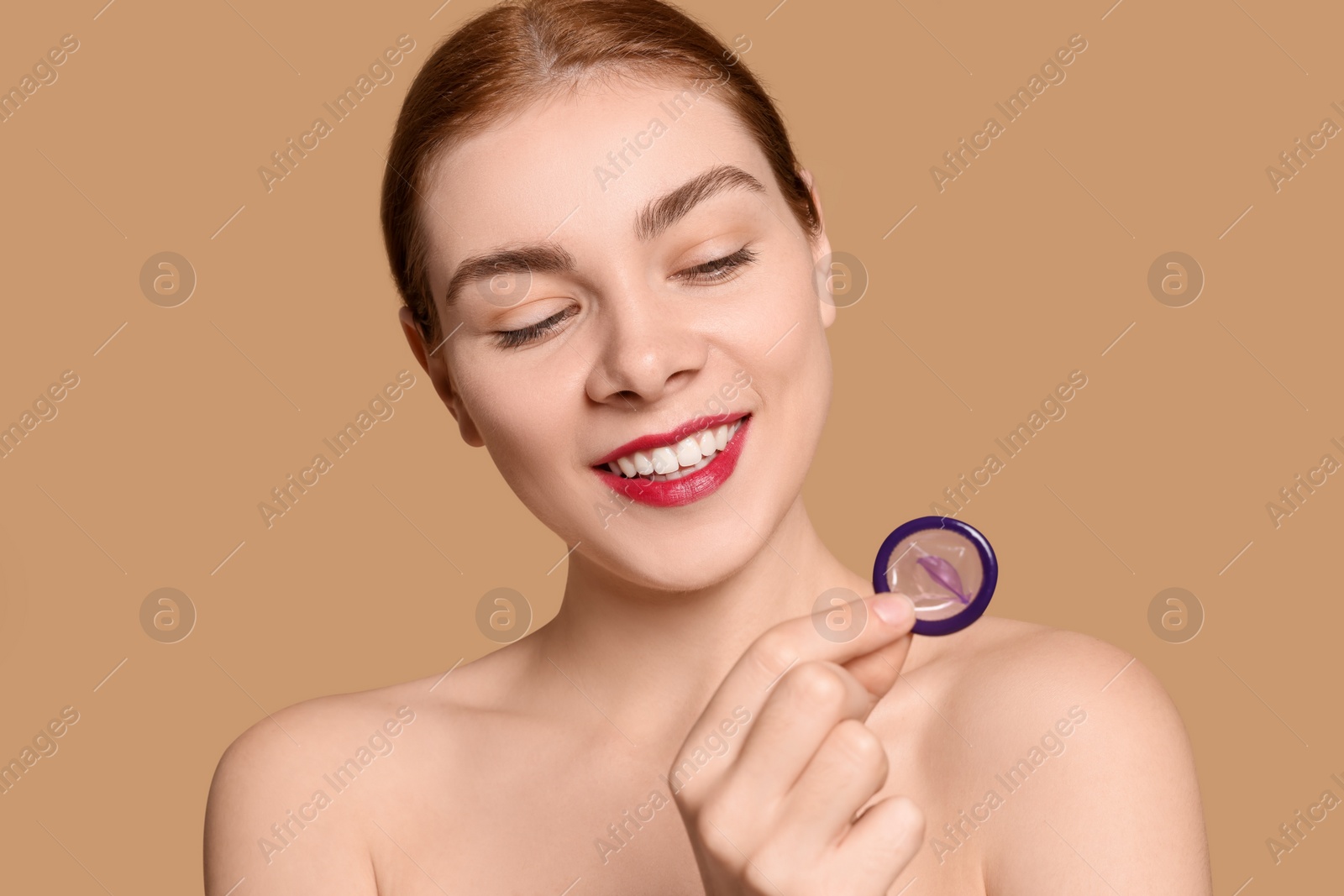 Photo of Woman holding condom on beige background. Safe sex