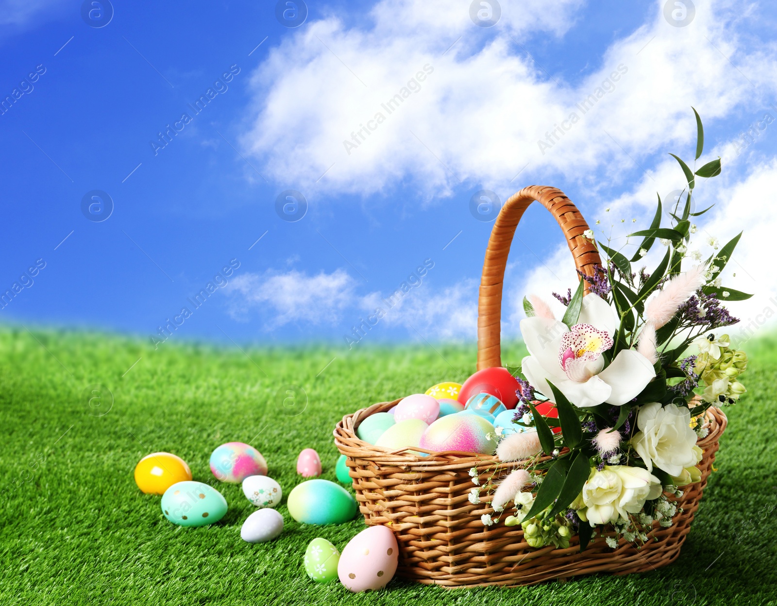 Image of Wicker basket with Easter eggs on green grass outdoors, space for text