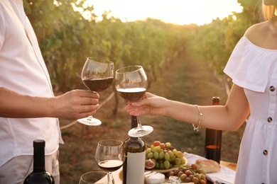 Photo of Couple with glasses of wine in vineyard on sunny day, closeup