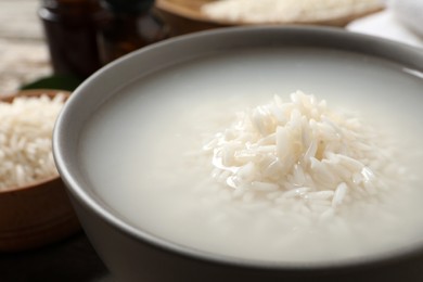 Photo of Bowl with rice soaked in water on table, closeup