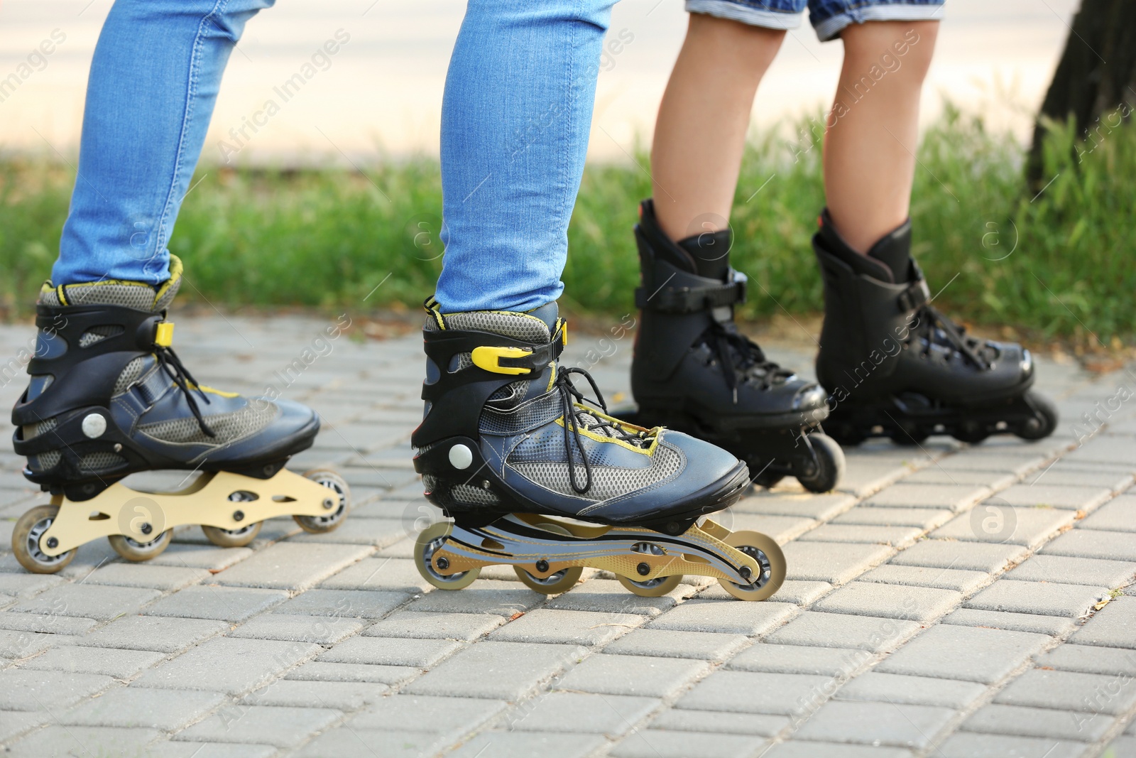 Photo of Father and son roller skating in park, closeup of legs