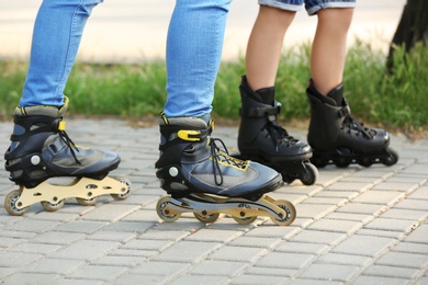 Father and son roller skating in park, closeup of legs