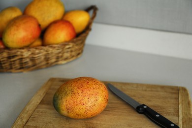 Photo of Tasty mango and knife on wooden board indoors