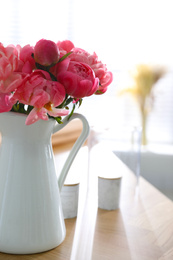 Beautiful bouquet of fragrant peonies in vase on table indoors