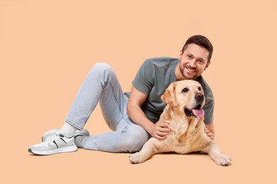 Photo of Man hugging with adorable Labrador Retriever dog on beige background. Lovely pet