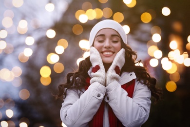 Photo of Happy young woman outdoors in evening. Christmas celebration