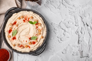 Photo of Delicious hummus with chickpeas and paprika served on white textured table, flat lay. Space for text