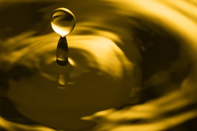 Splash of golden oily liquid with drop as background, closeup