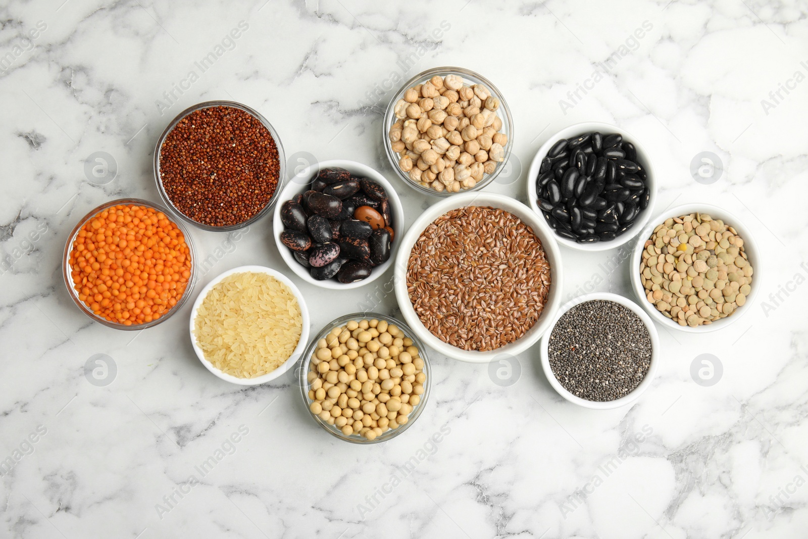 Photo of Different grains and seeds on white marble table, flat lay. Veggie diet