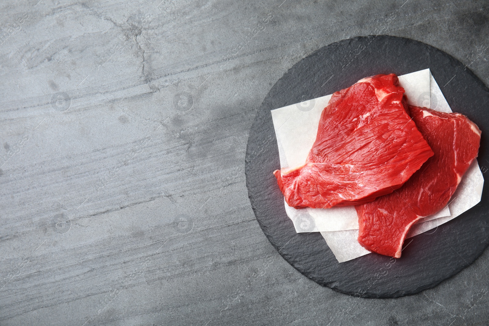 Photo of Fresh raw beef cut on grey table, top view. Space for text