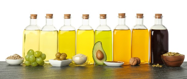 Vegetable fats. Bottles of different cooking oils and ingredients on wooden table against white background