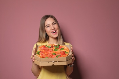 Attractive young woman with delicious pizza on color background