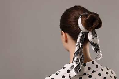 Photo of Woman with stylish bandana on light grey background, back view. Space for text