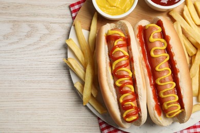 Photo of Delicious hot dogs with mustard, ketchup and potato fries on white wooden table, top view. Space for text