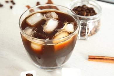 Glass of coffee drink with ice cubes on table