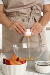 Photo of Woman beating egg into bowl at grey table, closeup. Cooking of delicious cake