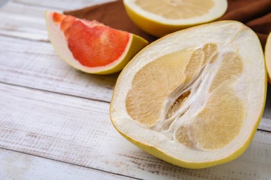 Photo of Different sorts of tasty pomelo fruits on white wooden table, closeup. Space for text