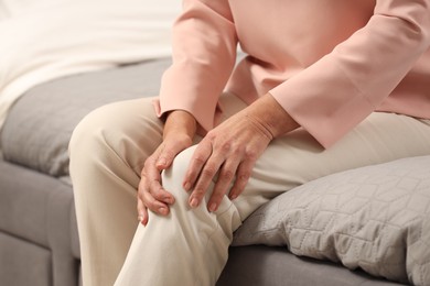 Photo of Mature woman suffering from knee pain on bed, closeup. Rheumatism symptom