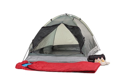 Photo of Comfortable grey camping tent with red sleeping bag and sneakers on white background