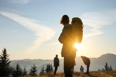 Photo of Tourists with backpacks in mountains on sunset