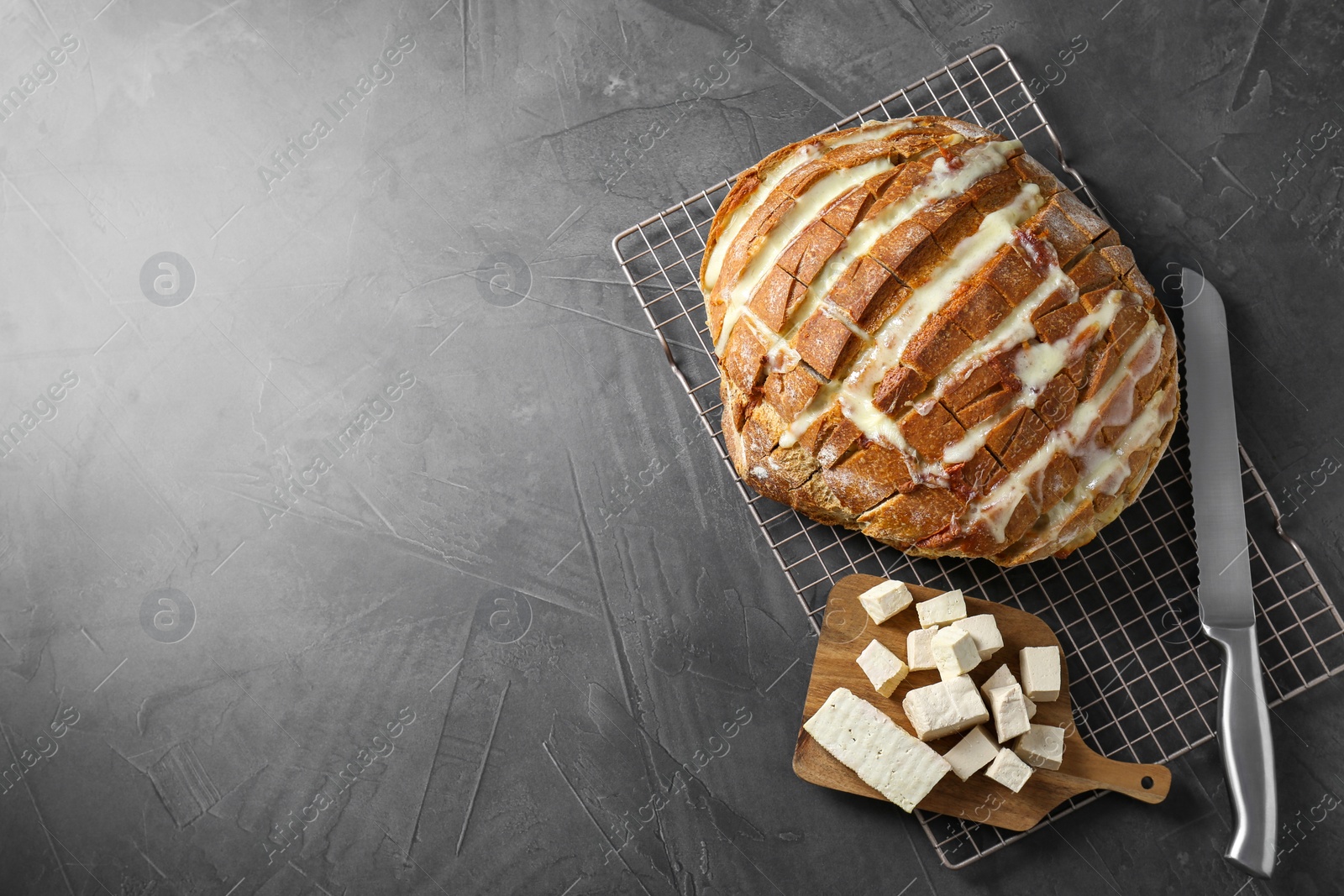 Photo of Freshly baked bread with tofu cheese and knife on black table, top view. Space for text