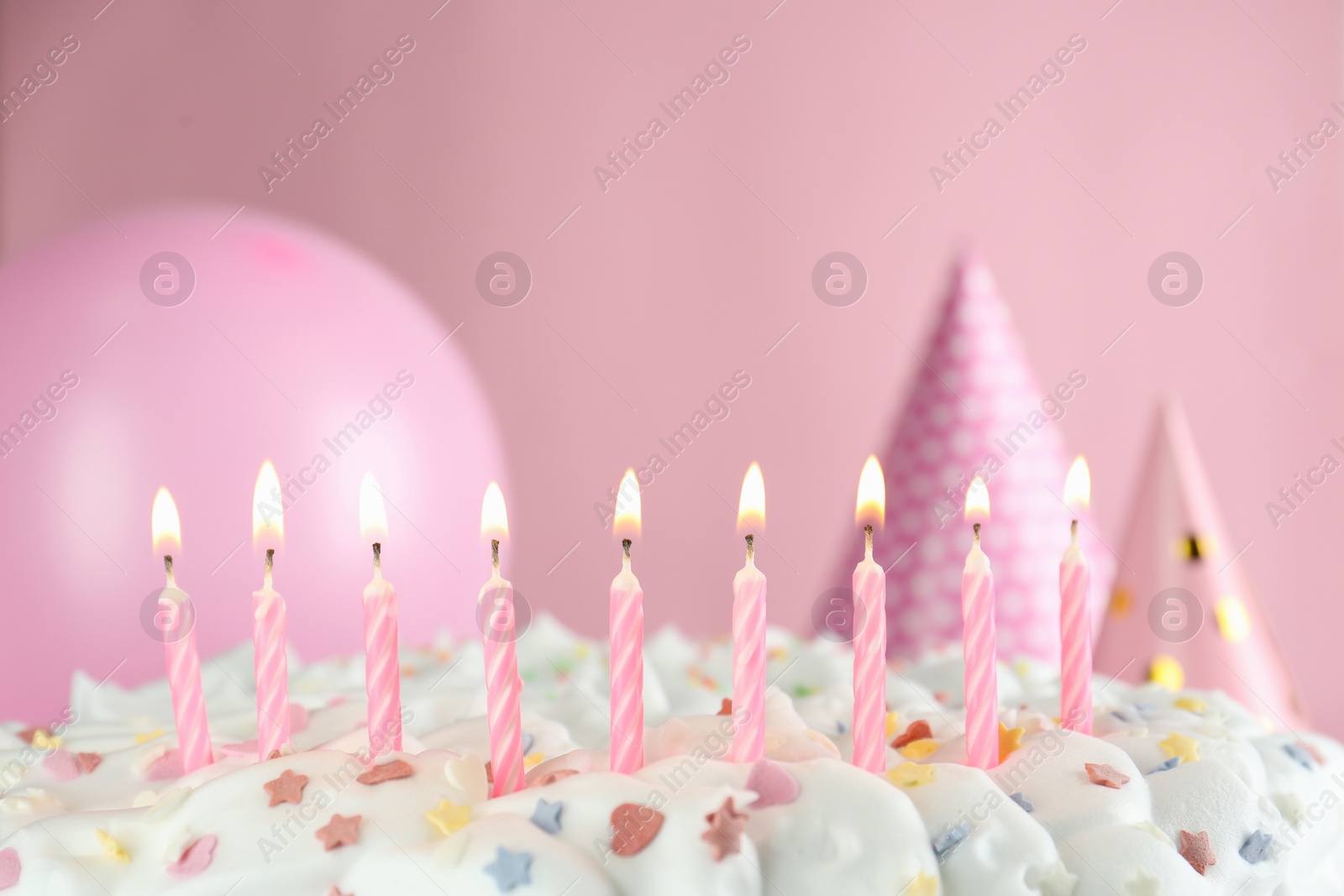 Photo of Birthday cake with burning candles on pink background, closeup