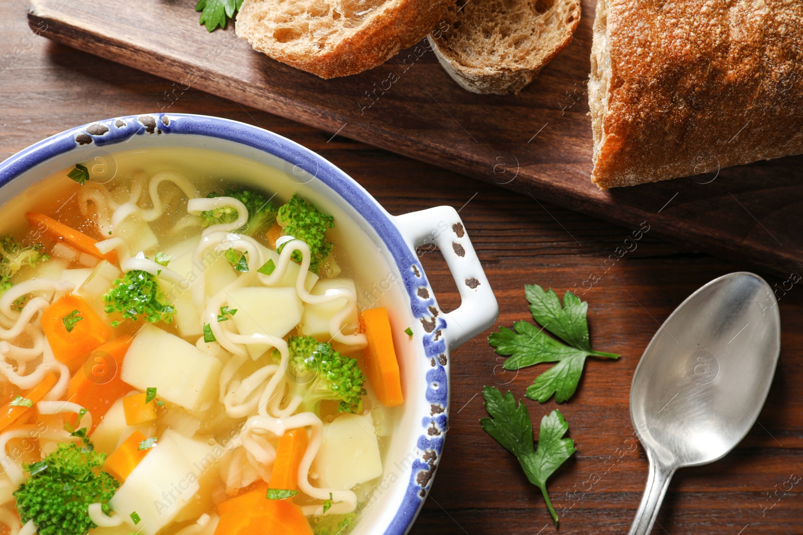 Photo of Dish of fresh homemade vegetable soup served on wooden table, top view