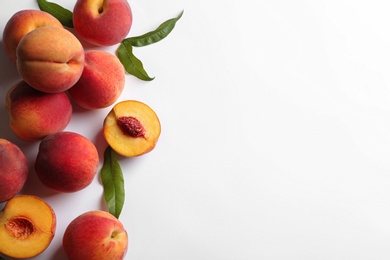 Photo of Fresh ripe peaches and green leaves on white background, flat lay. Space for text