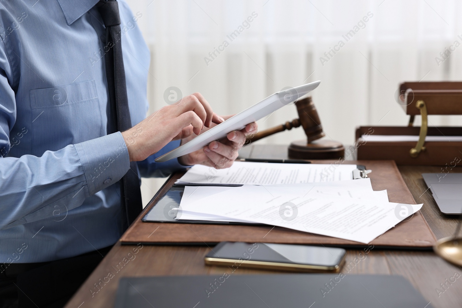 Photo of Lawyer using tablet at wooden table, closeup