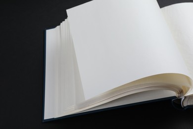 Photo of One open photo album on black background, closeup. Space for text