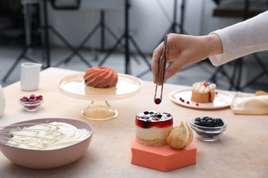 Photo of Food stylist creating composition with delicious dessert on table in photo studio, closeup