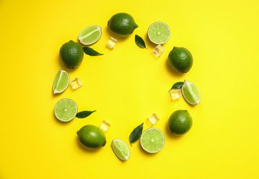 Photo of Flat lay composition with fresh juicy limes and ice cubes on yellow background. Space for text